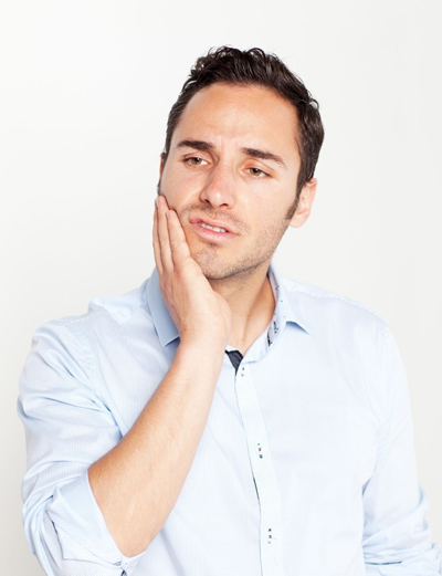 Brunette man holding the side of his face perhaps with a weird sensation in a dental crown or implant