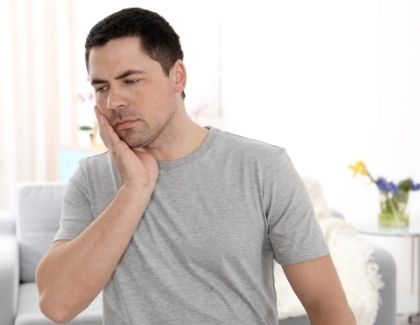 Man holding the side of his face, for information on dental crowns for acid reflux